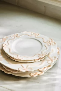 A white stoneware set of Benedita Bow Stoneware Side Plates with an embossed bow design. Elegant and top rated Anthropologie kitchenware for a hostess.